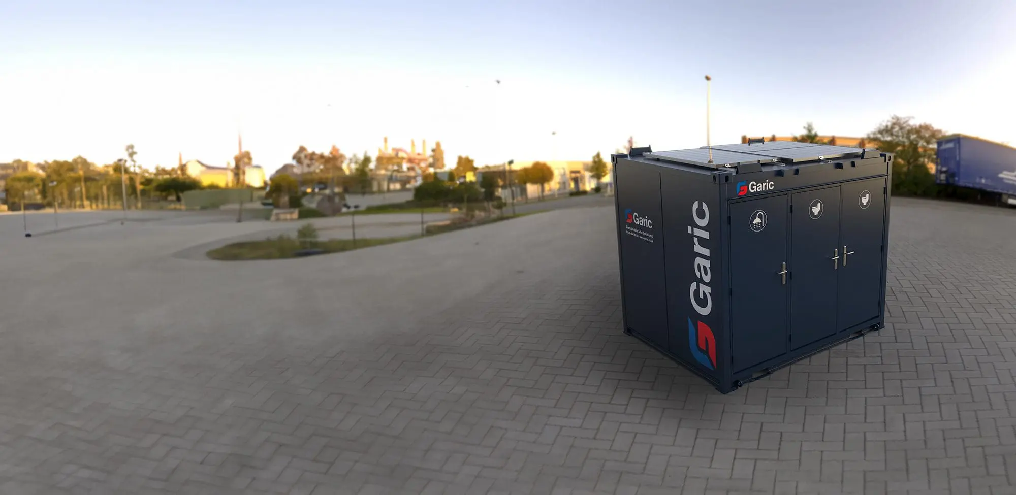 A 1+1 Toilet Block 10 sits on a paved area with a park and buildings in the background.