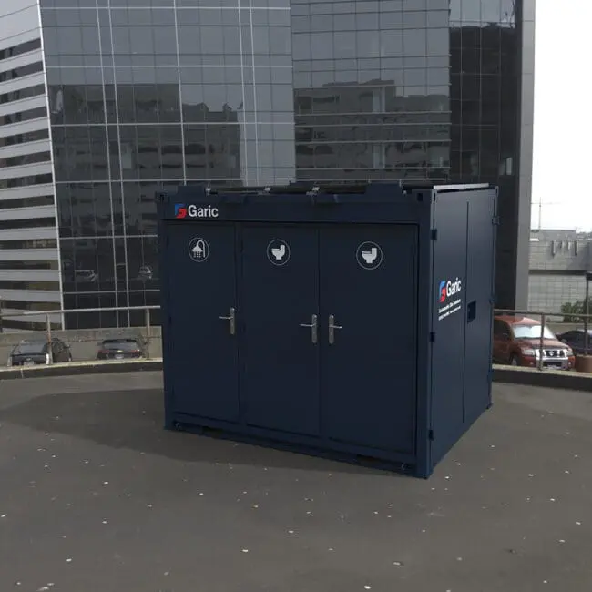 A 1+1 Toilet Block 10 unit sits on a rooftop, surrounded by tall office buildings and parked cars.