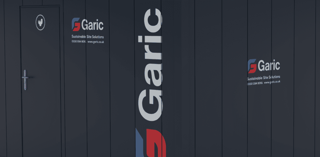A dark blue wall with the Garic Sustainable Site Solutions logo and contact info is shown alongside a 2+1 Toilet Block 12 door with a handle.