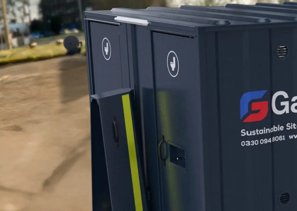 The Armadillo 18 Eco portable toilets, featuring dark blue exteriors with white hand symbols and company branding, are placed outdoors on a construction site.