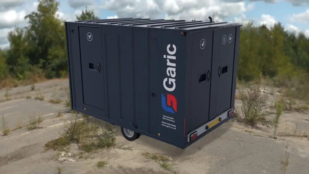 The Armadillo 12, a dark blue portable toilet trailer branded by Garic, is parked outdoors on a rough, overgrown surface.