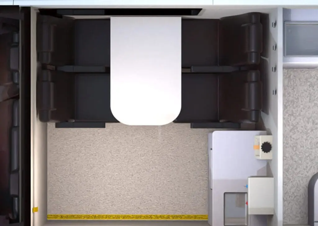 Top view of the Welfare Van Eco+ shows a compact room with a white table, black benches, carpeted floor, and a kitchenette area to the right.