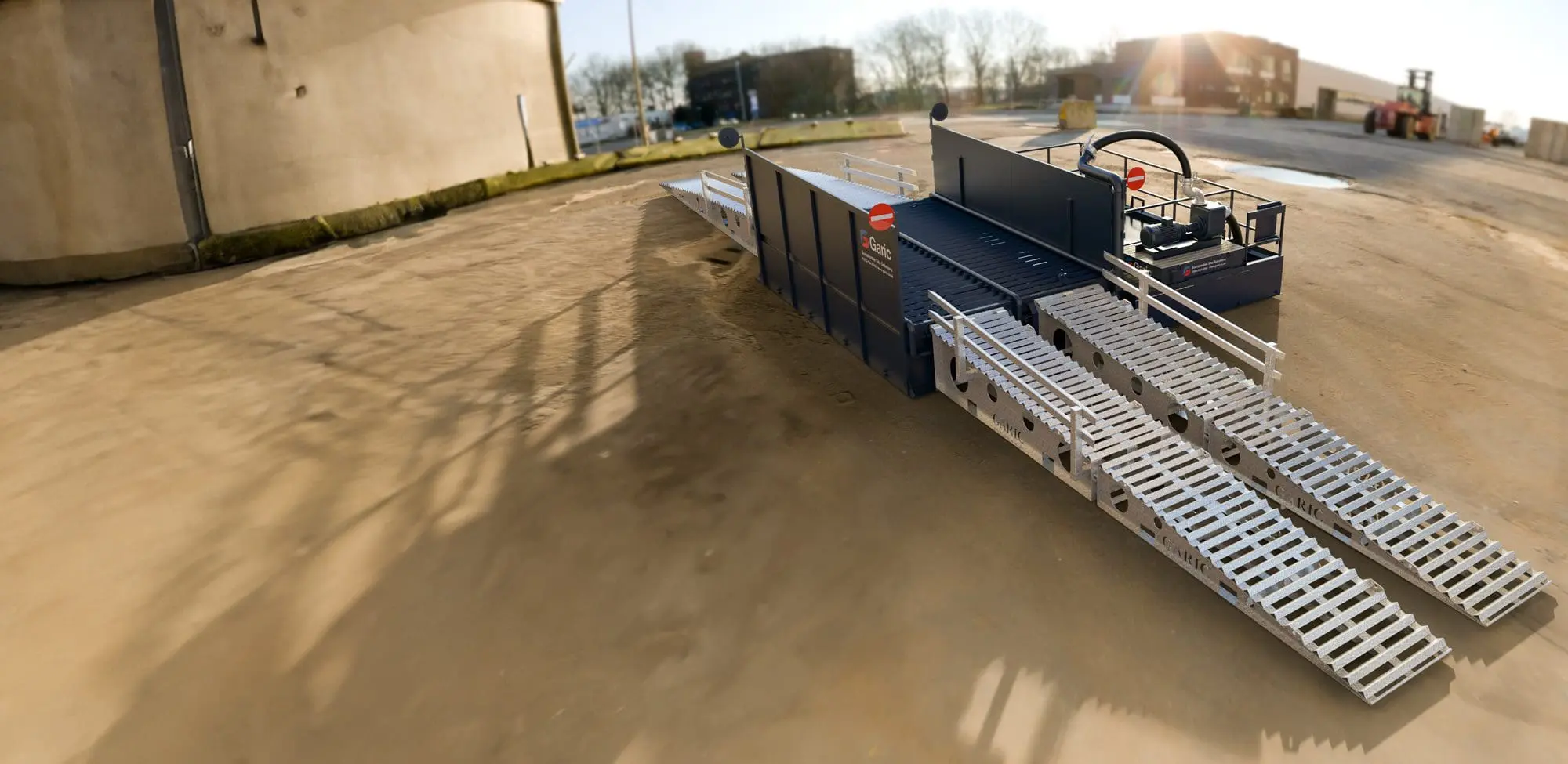Enviro Wheel Wash 24: Large industrial loading ramp featuring metal tracks and safety rails, designed for outdoor use on concrete surfaces.