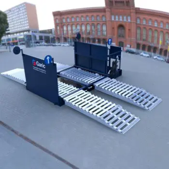 The Enviro Wheel Wash 14, a portable vehicle wash platform with ramps, is set up on pavement in front of a large brick building.