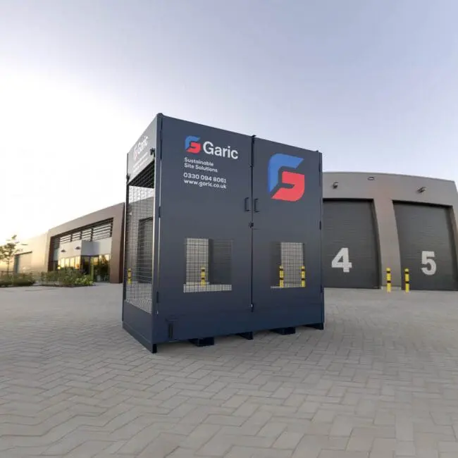 An Interceptor Drumstore, painted blue, is positioned outside a modern building featuring numbered doors and a paved courtyard.