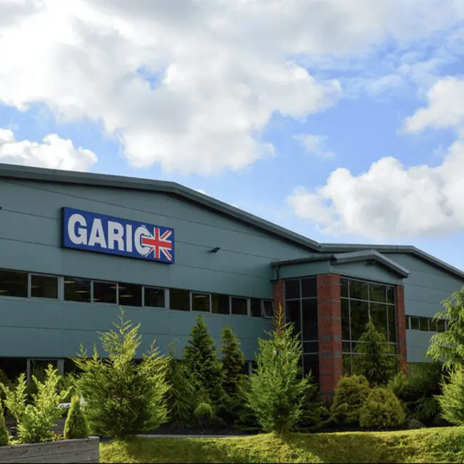 A modern industrial building with a GARIC sign and trees in front, under a partly cloudy sky.