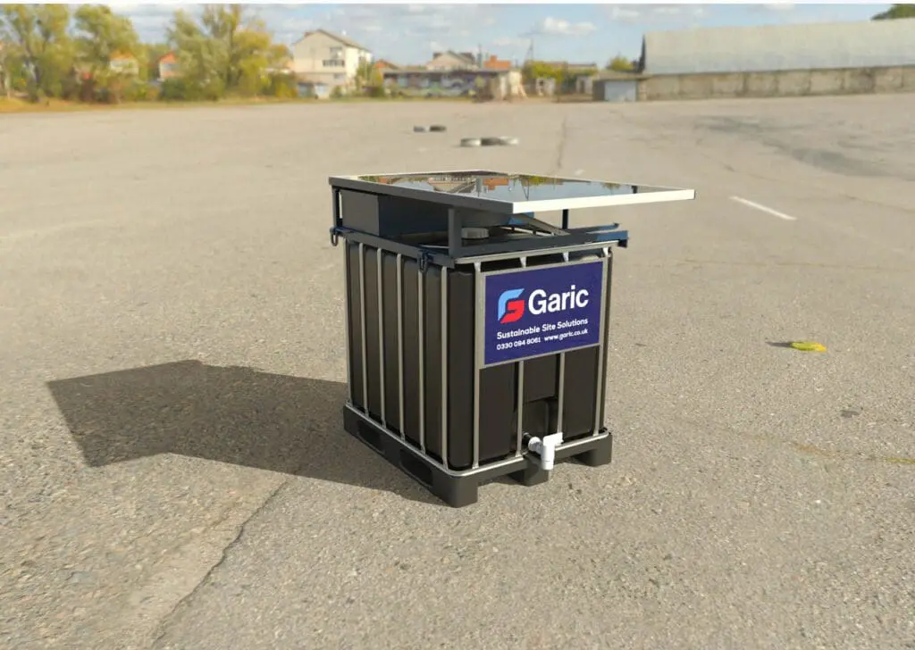 A Solar IBC 1000 sanitation unit, black with a solar panel, stands alone on an empty paved lot beneath a blue sky.