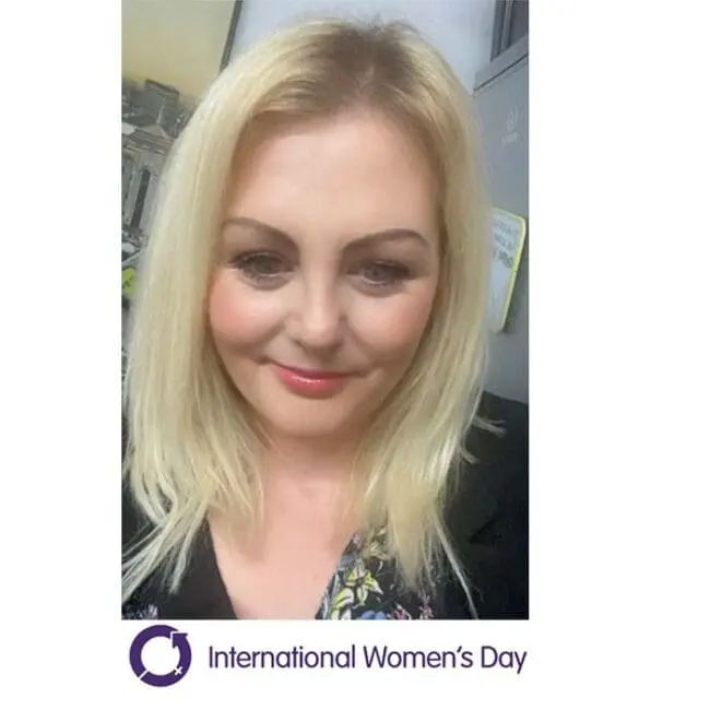 A woman with blonde hair smiling, with an International Womens Day logo and text at the bottom.