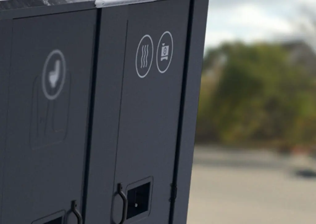 Close-up of the Armadillo 18, a gray vending or utility machine, featuring icons and a blurred background.