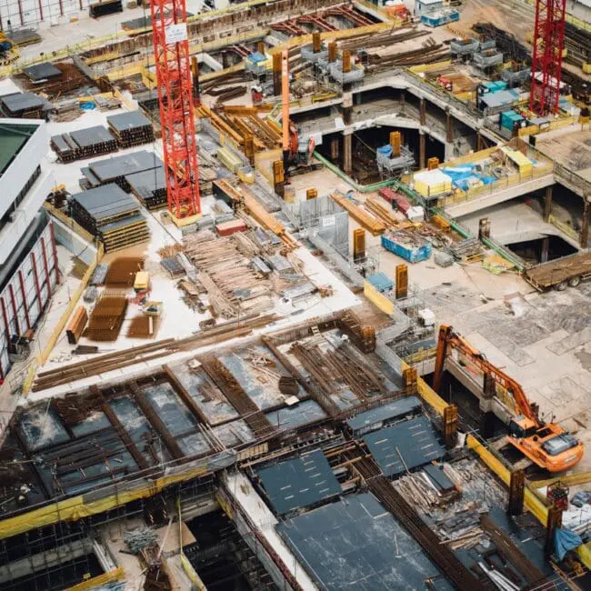 Aerial view of a busy construction site with cranes, machinery, and building materials.
