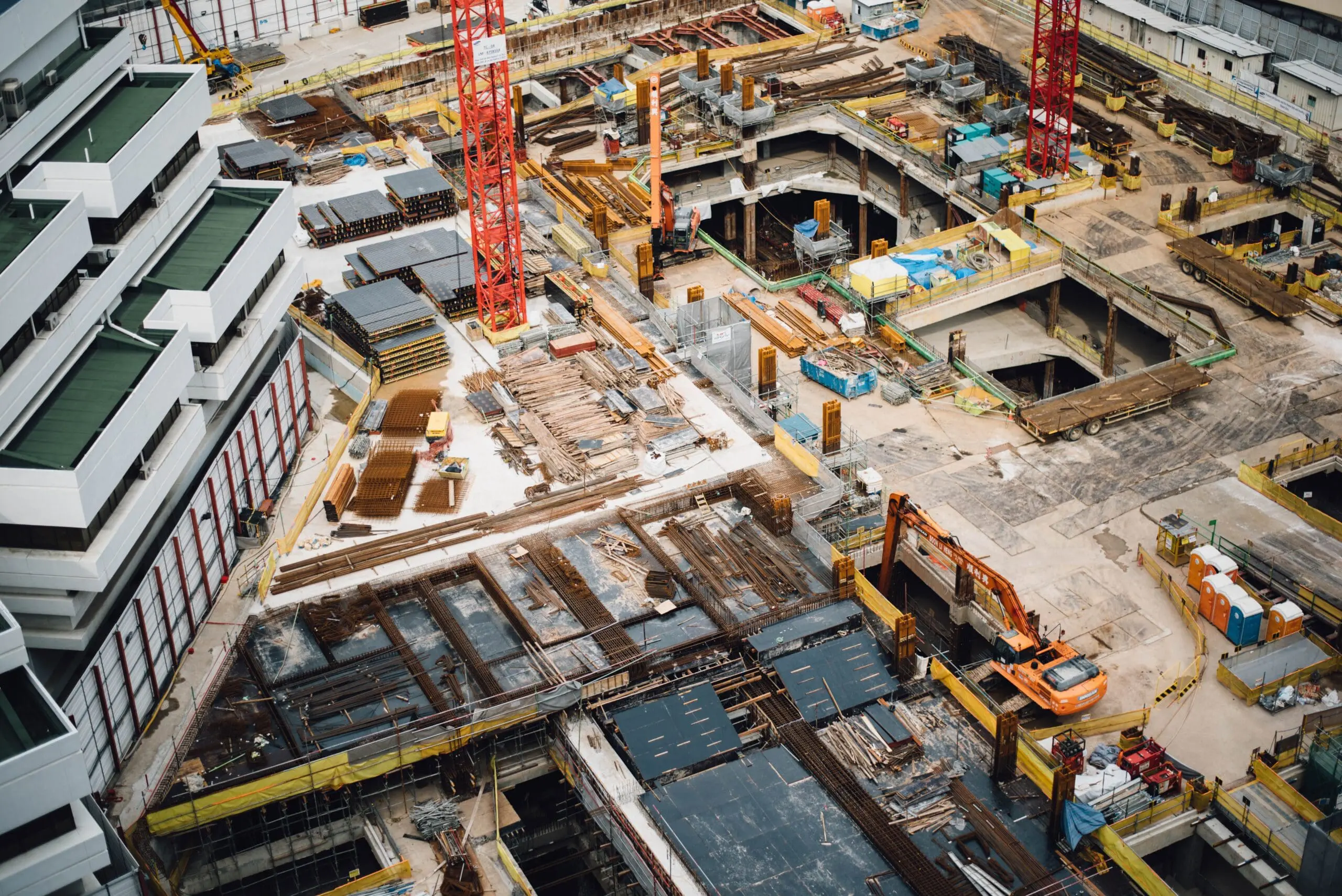 Aerial view of a busy construction site with cranes, machinery, and building materials.
