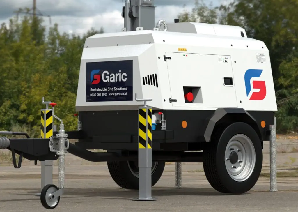 A “Garic” branded Hybrid Tower Light is parked outdoors on a paved surface near greenery.