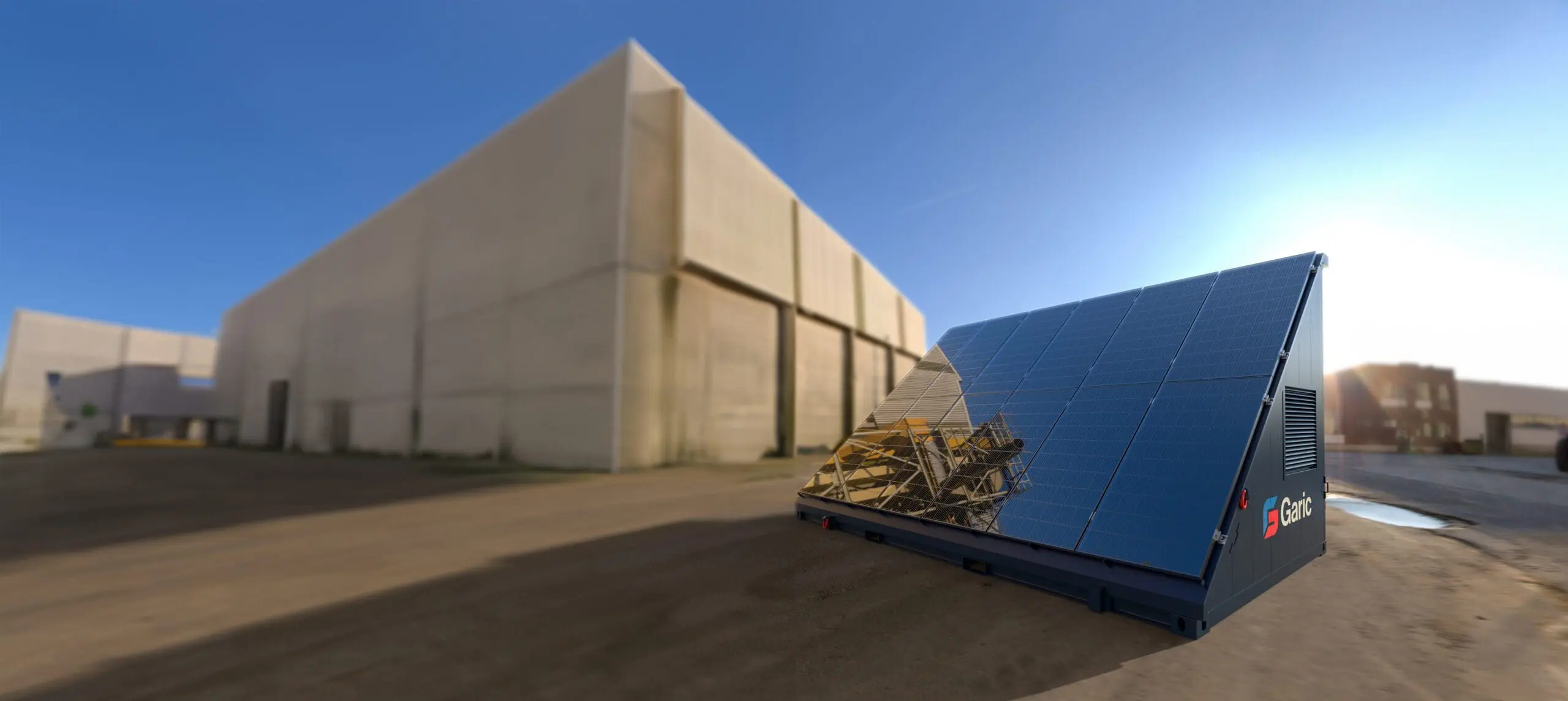 A Solar Energy Store 20 panel array is installed on a unit near large industrial buildings under a clear blue sky.