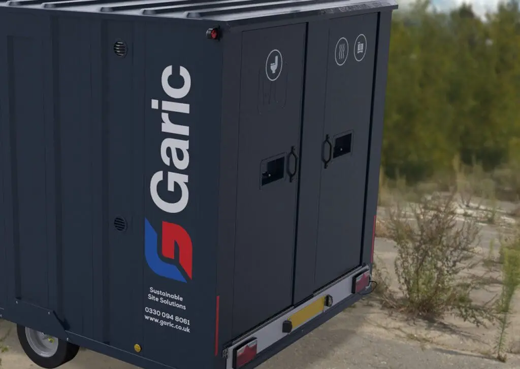 Dark blue Armadillo 12 portable site toilet unit with waste and recycling symbols on the doors, outdoors.