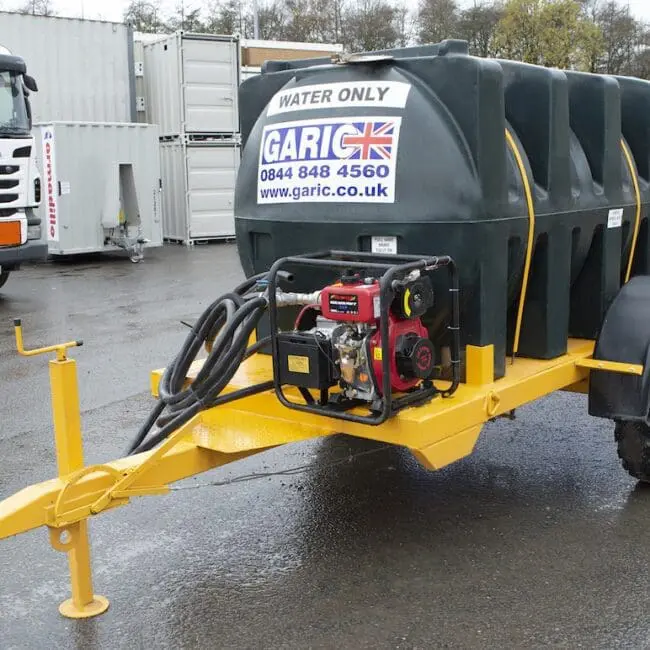 A mobile water tank trailer with a pump and hoses, labeled Water Only and Garic, parked outdoors.