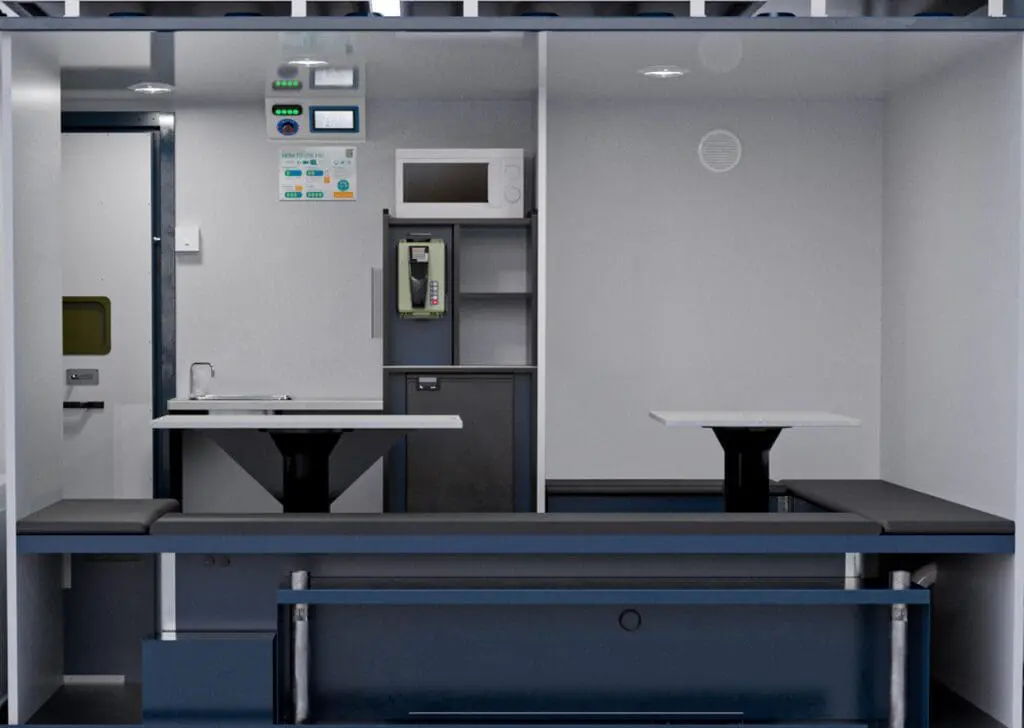 The Armadillo 18 Eco+ features a modern train compartment design with tables, benches, a sink, microwave, phone, and wall-mounted control panels.