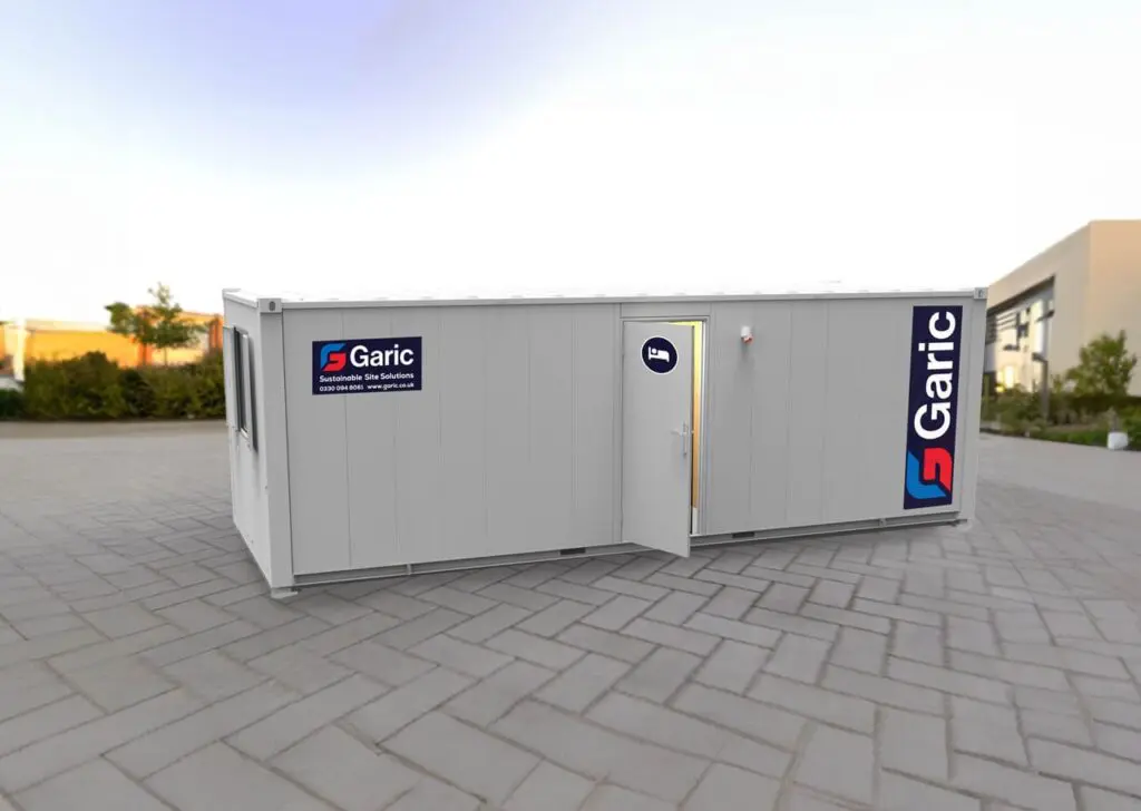 A white portable cabin with Garic logos, placed on a paved outdoor area with its door open.