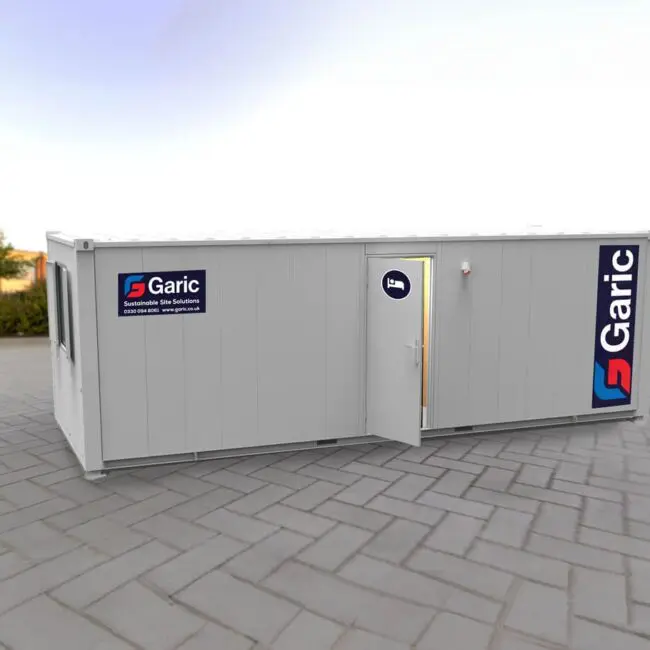 A white portable cabin with Garic logos, placed on a paved outdoor area with its door open.