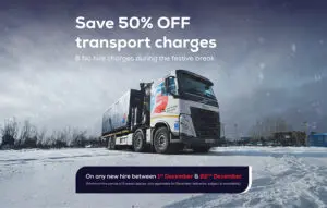 A large truck parked on snow with a 50% off transport charges festive offer displayed above.