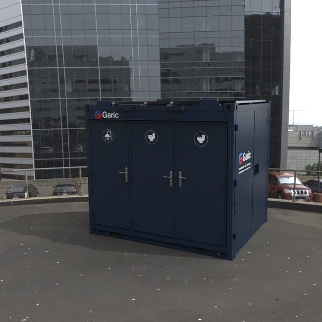 A 1+1 Toilet Block 10 unit sits on a rooftop, surrounded by tall office buildings and parked cars.