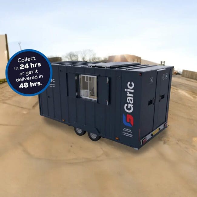 A dark gray Armadillo 18 Eco portable unit on wheels with a sign: Collect in 24 hrs or get it delivered in 48 hrs.