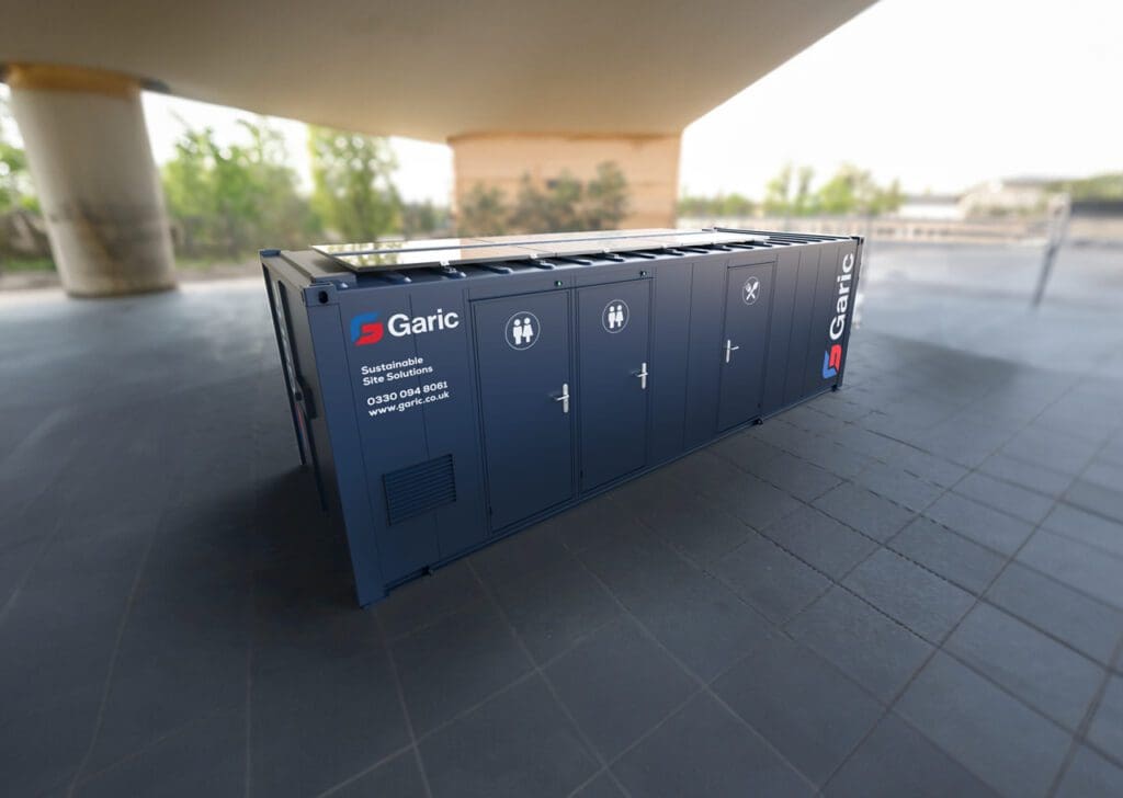 A blue Combi Cabin 24 Eco portable restroom unit sits outdoors on a tiled surface under a large structure.