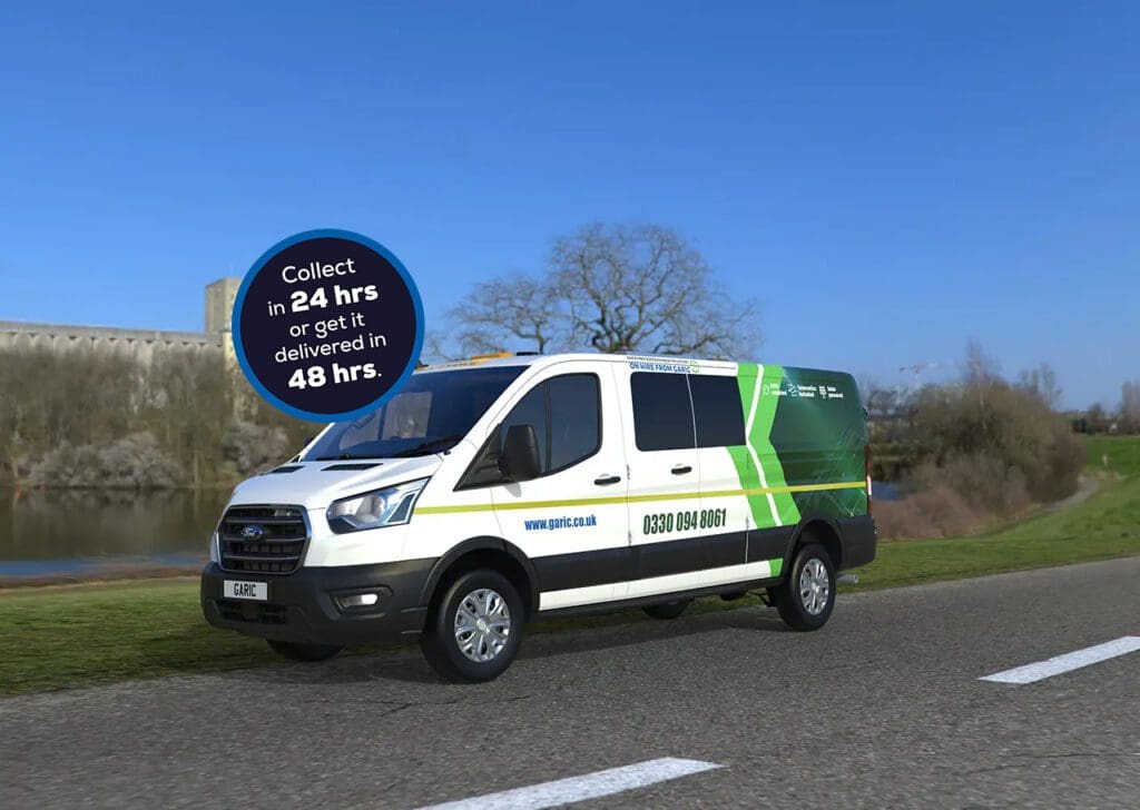 A Welfare Van Eco+ in white and green is driving on a road by a river, with a blue sky in the background.
