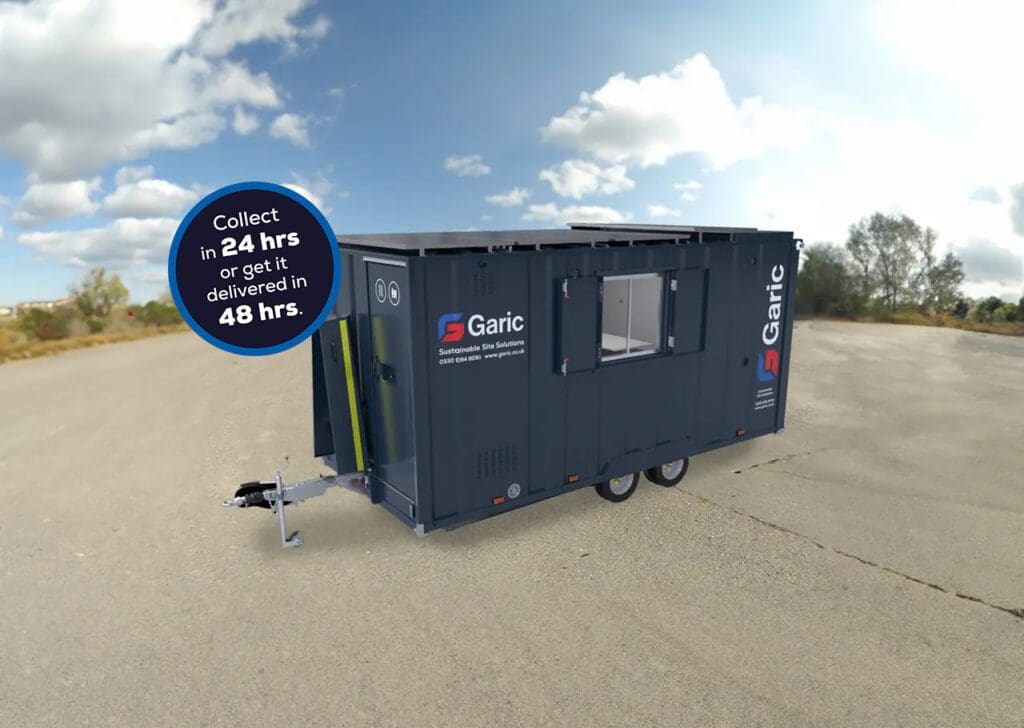 A dark blue Armadillo 18 Eco+ portable unit on wheels in an empty outdoor area, displaying a sign about collection and delivery times.