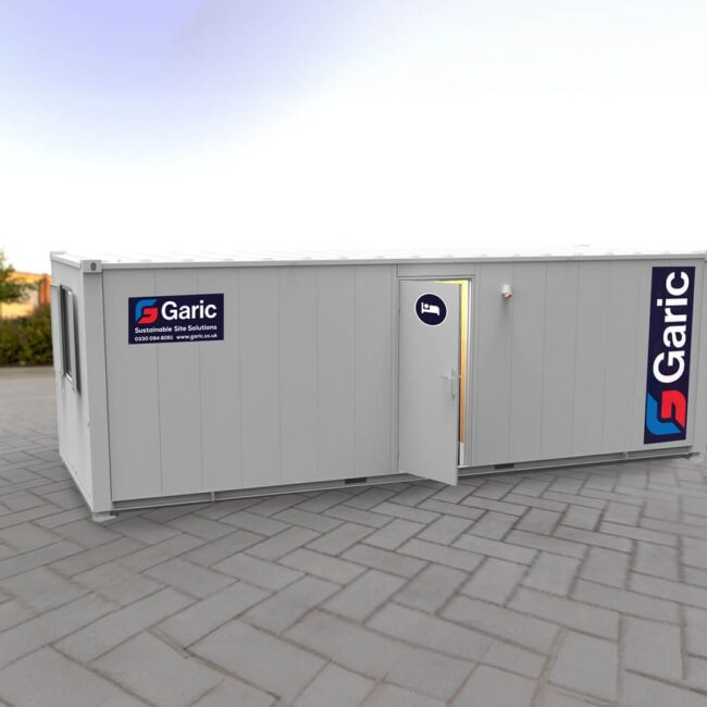 A white portable cabin with Garic logos, placed on a paved outdoor area with its door open.